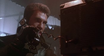 Movie still from “Hardware” (1990), directed by Richard Stanley – A man holding a gun in his hand; Close Up shot, Low angle