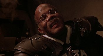 Movie still from “Hardware” (1990), directed by Richard Stanley – An older man wearing a suit and tie; Close Up shot, Low angle