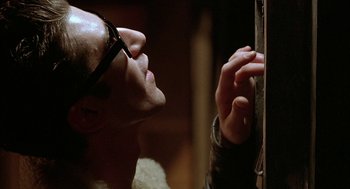 Movie still from “Hardware” (1990), directed by Richard Stanley – A man with glasses looking into a mirror; Close Up shot, Low angle