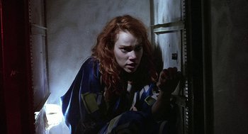 Movie still from “Hardware” (1990), directed by Richard Stanley – A red haired woman leaning against a wall; Medium shot, Low angle