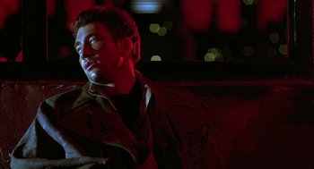 Movie still from “Hardware” (1990), directed by Richard Stanley – A young man is sitting on a bench in the dark; Close Up shot, High angle