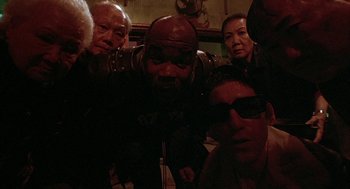 Movie still from “Hardware” (1990), directed by Richard Stanley – A group of people standing around each other in the dark; Close Up shot, Low angle
