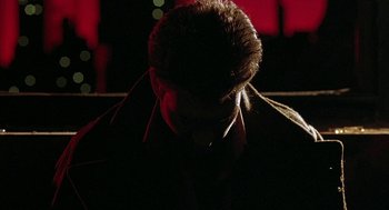 Movie still from “Hardware” (1990), directed by Richard Stanley – A man in a dark room looking down at his head; Close Up shot, Low angle