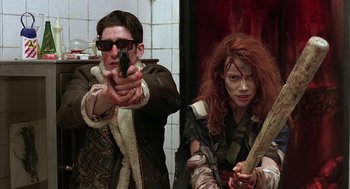 Movie still from “Hardware” (1990), directed by Richard Stanley – A man and a woman holding guns in a bathroom; Medium shot, Low angle