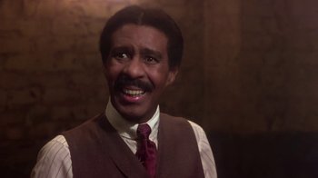 Movie still from “Harlem Nights” (1989), directed by Eddie Murphy – A man in a vest and tie smiling for the camera; Close Up shot, Low angle