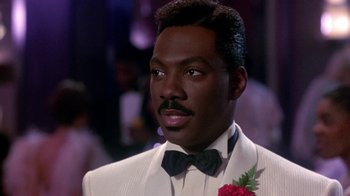 Movie still from “Harlem Nights” (1989), directed by Eddie Murphy – A person wearing a suit and a bow tie; Close Up shot, Over the shoulder angle
