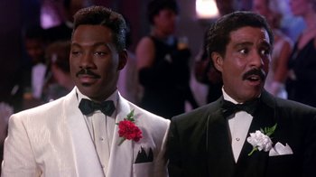 Movie still from “Harlem Nights” (1989), directed by Eddie Murphy – A couple of men standing next to each other in tuxedos; Medium shot, Low angle