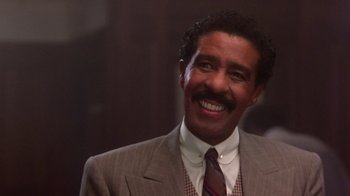 Movie still from “Harlem Nights” (1989), directed by Eddie Murphy – A man in a suit and tie smiling for the camera; Close Up shot, Low angle