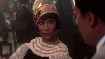Movie still from “Harlem Nights” (1989), directed by Eddie Murphy – A person wearing a dress and a hat; Close Up shot, Over the shoulder angle