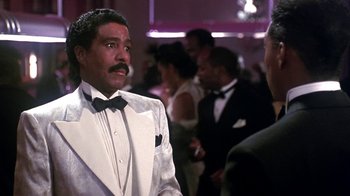 Movie still from “Harlem Nights” (1989), directed by Eddie Murphy – A man in a white suit and a black bow tie; Medium shot, Low angle