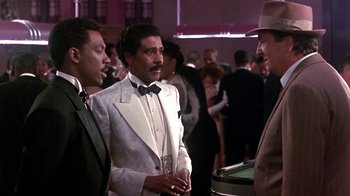 Movie still from “Harlem Nights” (1989), directed by Eddie Murphy – A group of men standing next to each other at an event; Medium shot, Over the shoulder angle