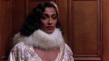 Movie still from “Harlem Nights” (1989), directed by Eddie Murphy – A woman in a white dress and a white fur collar; Close Up shot, Low angle