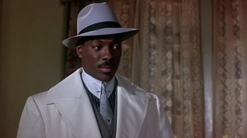Movie still from “Harlem Nights” (1989), directed by Eddie Murphy – A man wearing a hat and a white coat; Close Up shot, Low angle
