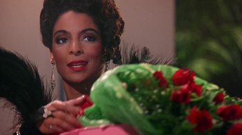 Movie still from “Harlem Nights” (1989), directed by Eddie Murphy – A person holding a bouquet of flowers; Close Up shot, Over the shoulder angle