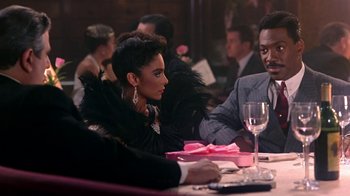 Movie still from “Harlem Nights” (1989), directed by Eddie Murphy – A man and a woman sitting at a dinner table; Medium shot, Over the shoulder angle