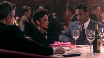 Movie still from “Harlem Nights” (1989), directed by Eddie Murphy – A man and a woman sitting at a dinner table; Medium shot, Over the shoulder angle