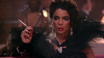 Movie still from “Harlem Nights” (1989), directed by Eddie Murphy – A woman in a black dress smoking a cigarette; Close Up shot, Over the shoulder angle