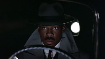 Movie still from “Harlem Nights” (1989), directed by Eddie Murphy – A man in a hat and a coat and tie; Close Up shot, Low angle