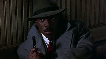 Movie still from “Harlem Nights” (1989), directed by Eddie Murphy – A man in a fedora holding a cell phone; Close Up shot, Low angle