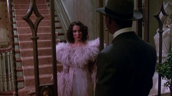 Movie still from “Harlem Nights” (1989), directed by Eddie Murphy – A woman in a pink dress standing in front of a man in a suit and hat; Medium shot, Over the shoulder angle