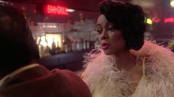 Movie still from “Harlem Nights” (1989), directed by Eddie Murphy – A woman in a white dress and a white feather boa; Close Up shot, Over the shoulder angle