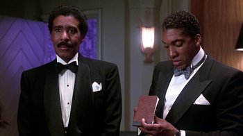 Movie still from “Harlem Nights” (1989), directed by Eddie Murphy – Two men in tuxedos are looking at a book; Medium shot, Low angle