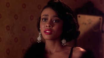 Movie still from “Harlem Nights” (1989), directed by Eddie Murphy – A young woman with long black hair wearing a black dress and diamond earrings; Close Up shot, Over the shoulder angle