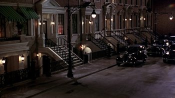 Movie still from “Harlem Nights” (1989), directed by Eddie Murphy – A car parked on the side of the road in front of a building; Extreme Wide shot, High angle