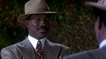 Movie still from “Harlem Nights” (1989), directed by Eddie Murphy – A man in a suit and hat is looking at the camera; Close Up shot, Over the shoulder angle