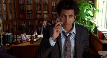 Movie still from “Harold & Kumar Go to White Castle” (2004), directed by Danny Leiner – A man talking on a cell phone in front of another man; Medium shot, High angle