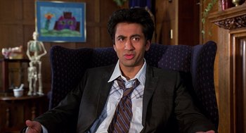 Movie still from “Harold & Kumar Go to White Castle” (2004), directed by Danny Leiner – A man in a suit and tie sitting in a chair; Close Up shot, Low angle