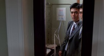Movie still from “Harold & Kumar Go to White Castle” (2004), directed by Danny Leiner – A man in a suit and tie standing in front of a mirror in an office; Medium shot, Over the shoulder angle