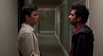 Movie still from “Harold & Kumar Go to White Castle” (2004), directed by Danny Leiner – Two young men standing next to each other in a hallway; Medium shot, Over the shoulder angle