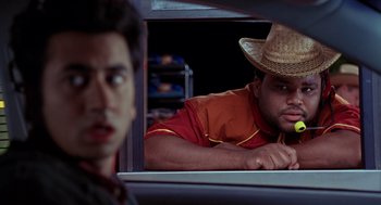 Movie still from “Harold & Kumar Go to White Castle” (2004), directed by Danny Leiner – A man wearing a straw hat sitting in the back of a car looking out the window; Close Up shot, Over the shoulder angle