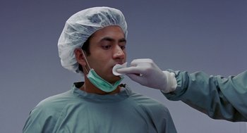 Movie still from “Harold & Kumar Go to White Castle” (2004), directed by Danny Leiner – A doctor is putting a surgical mask on a patient's face; Close Up shot, Over the shoulder angle
