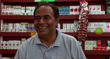 Movie still from “Harold & Kumar Go to White Castle” (2004), directed by Danny Leiner – A man standing in front of shelves of cigarettes; Medium shot, Low angle