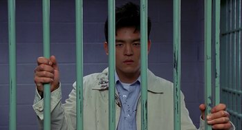 Movie still from “Harold & Kumar Go to White Castle” (2004), directed by Danny Leiner – A man behind a metal fence in a jail cell; Medium shot, Low angle