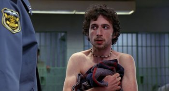 Movie still from “Harold & Kumar Go to White Castle” (2004), directed by Danny Leiner – A man holding a towel while standing next to a wall; Close Up shot, Over the shoulder angle