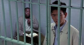 Movie still from “Harold & Kumar Go to White Castle” (2004), directed by Danny Leiner – Two men are sitting behind bars in a cell; Medium shot, High angle