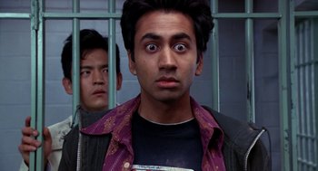 Movie still from “Harold & Kumar Go to White Castle” (2004), directed by Danny Leiner – A man standing next to another man behind bars; Close Up shot, Low angle