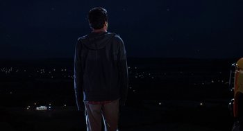 Movie still from “Harold & Kumar Go to White Castle” (2004), directed by Danny Leiner – A man standing on a hill at night looking at the sky; Wide shot, Over the shoulder angle