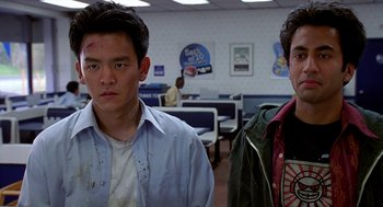 Movie still from “Harold & Kumar Go to White Castle” (2004), directed by Danny Leiner – Two young men standing next to each other in an office; Close Up shot, Low angle