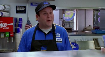 Movie still from “Harold & Kumar Go to White Castle” (2004), directed by Danny Leiner – A man in a blue and black uniform sitting at a table; Medium shot, Over the shoulder angle