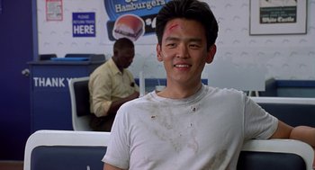 Movie still from “Harold & Kumar Go to White Castle” (2004), directed by Danny Leiner – A young man with a shaved head is smiling for the camera; Close Up shot, Over the shoulder angle