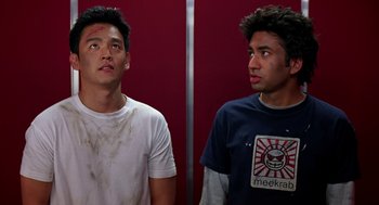 Movie still from “Harold & Kumar Go to White Castle” (2004), directed by Danny Leiner – Two young men standing next to each other in front of a red wall; Medium shot, Low angle
